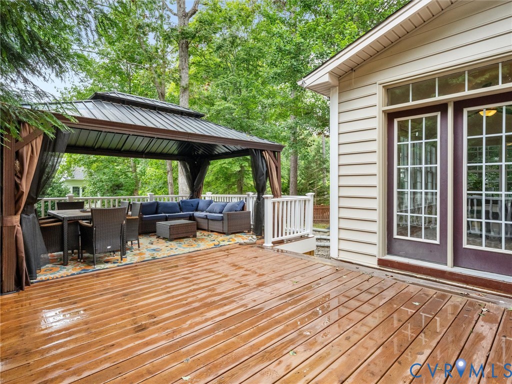 Expansive wood-finish deck with a built-in gazebo featuring a metal roof and privacy screens