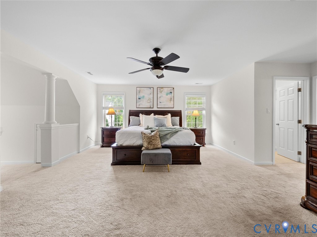 Spacious room featuring neutral carpeting, a ceiling fan, and multiple windows with natural light