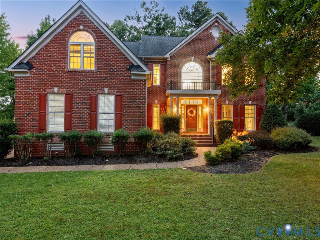 Brick exterior with a covered entry, arched windows, and landscaped grounds