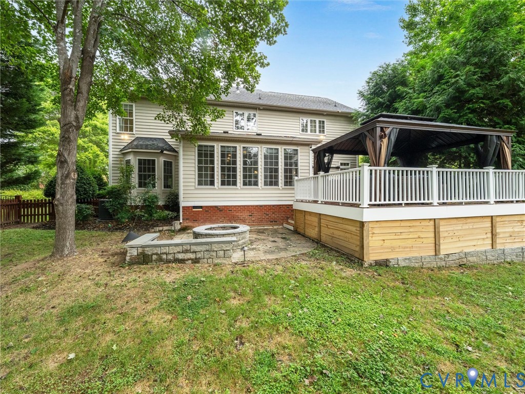 Expansive backyard retreat featuring a two-tier composite deck with white railings, pergola-covered lounge area, and mature tree canopy