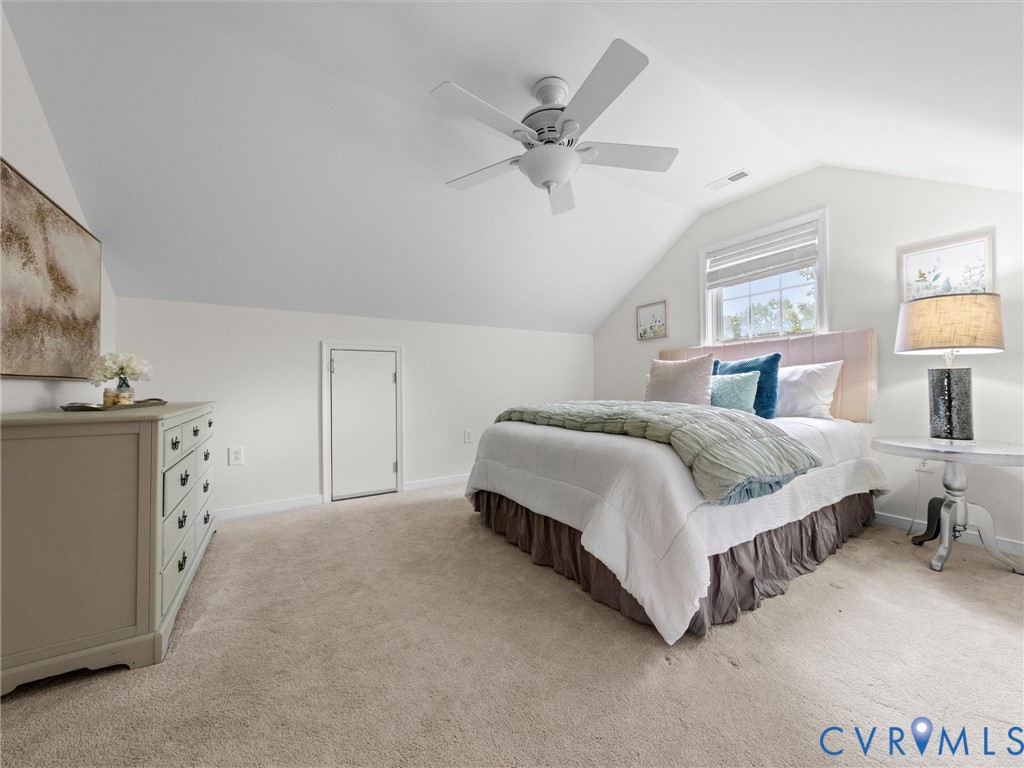 Spacious primary bedroom suite featuring vaulted ceilings, ceiling fan, abundant natural light from multiple windows, neutral carpet flooring, and an attached dresser with drawer storage