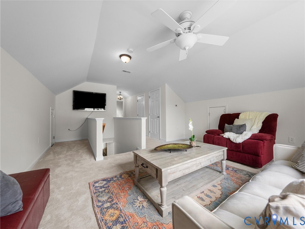 Carpeted loft area featuring a ceiling fan, sloped ceilings, and white painted walls