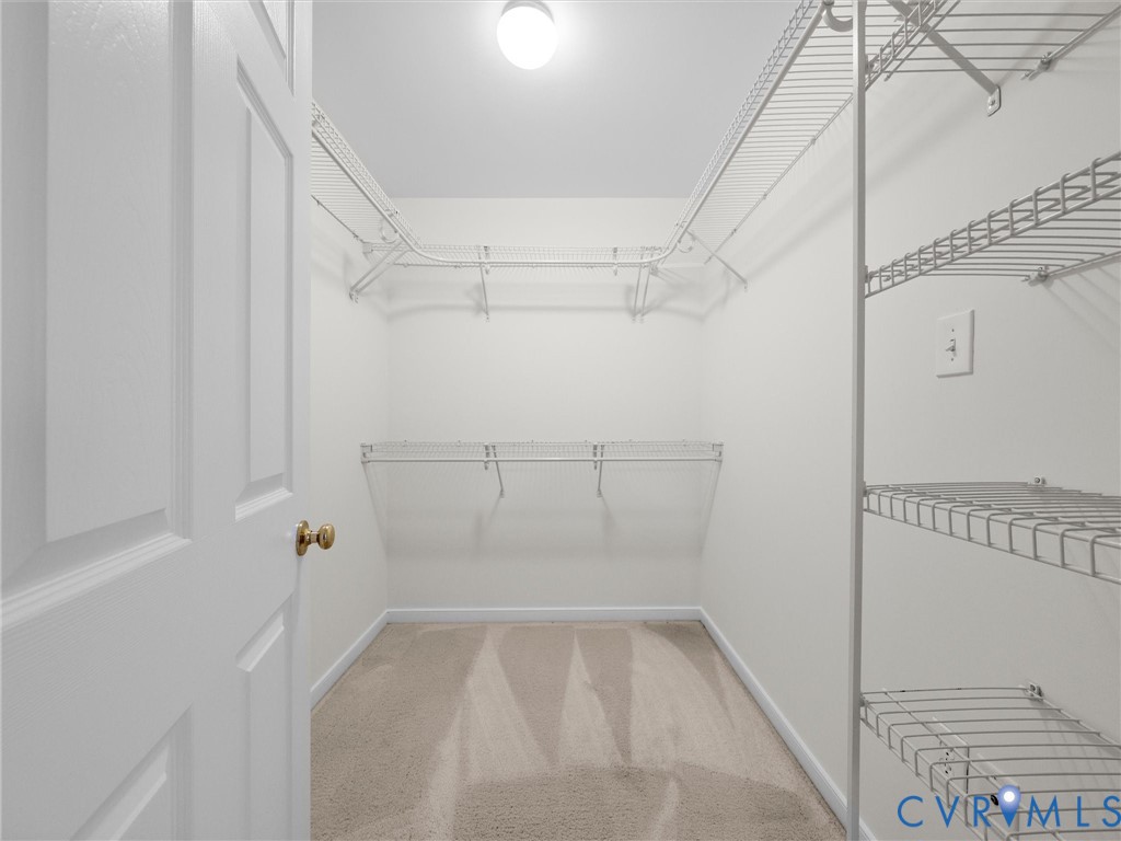 Walk-in closet with carpet flooring, white wire shelving, and overhead lighting