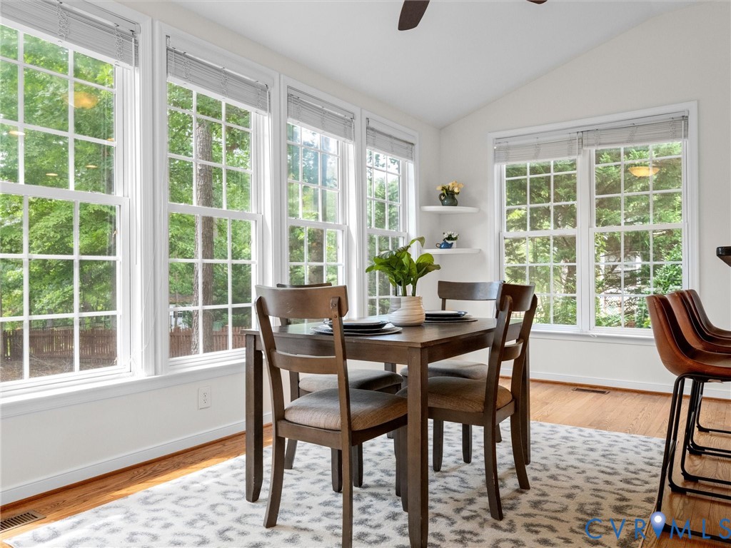 Vaulted ceiling with a ceiling fan, multiple tall windows, recessed lighting, and wood flooring