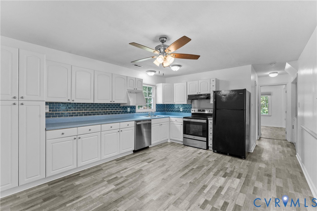 Kitchen featuring white cabinetry, blue countertops, tile backsplash, stainless steel appliances, and wood-finish flooring Kitchen featuring white cabinetry, blue countertops, tile backsplash, stainless steel appliances, and wood-finish flooring