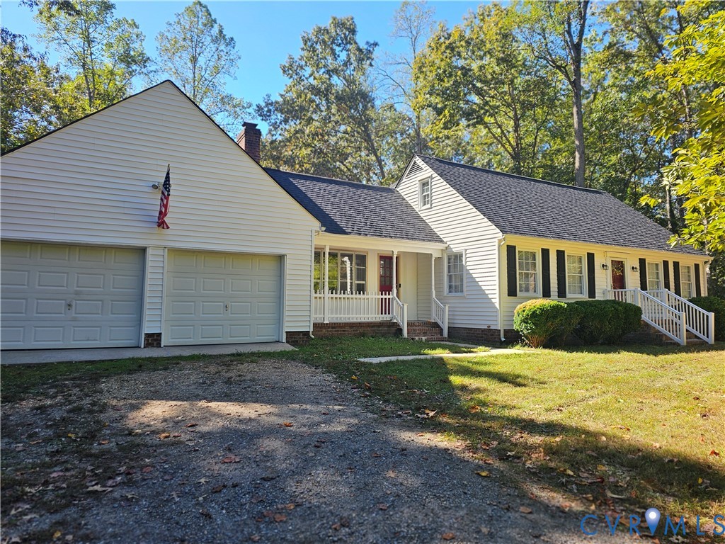 Exterior featuring white horizontal siding, a two-car garage, multi-gabled roofline, covered front porches with balustrades, and multi-pane windows with shutters