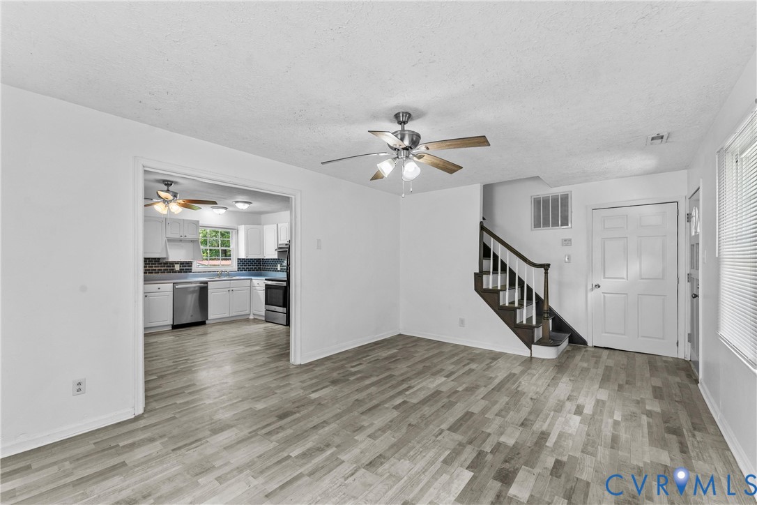 Wood-finish flooring throughout, bright white walls, and a ceiling fan with light fixture Wood-finish flooring throughout, bright white walls, and a ceiling fan with light fixture