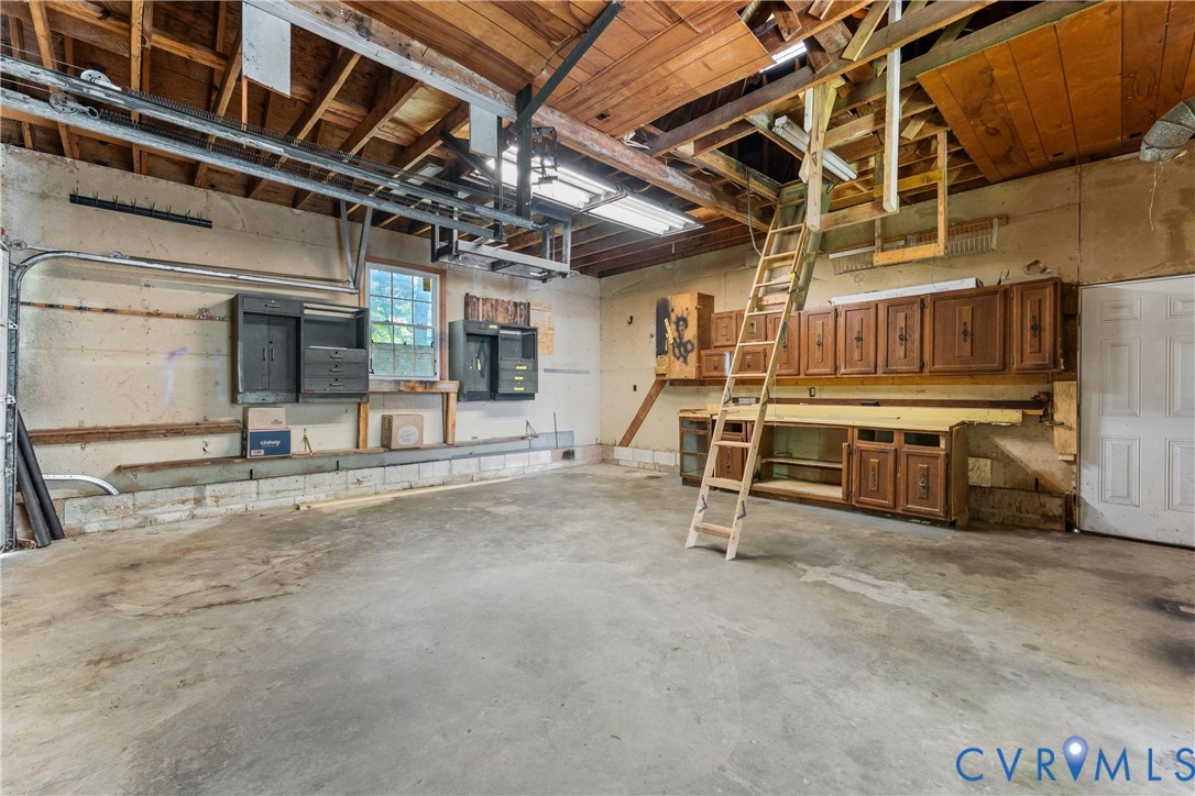 Concrete flooring, exposed wood beam ceiling, built-in cabinetry, and a window for natural light