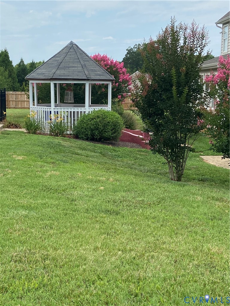 White gazebo with a dark shingle roof and surrounding landscaping
