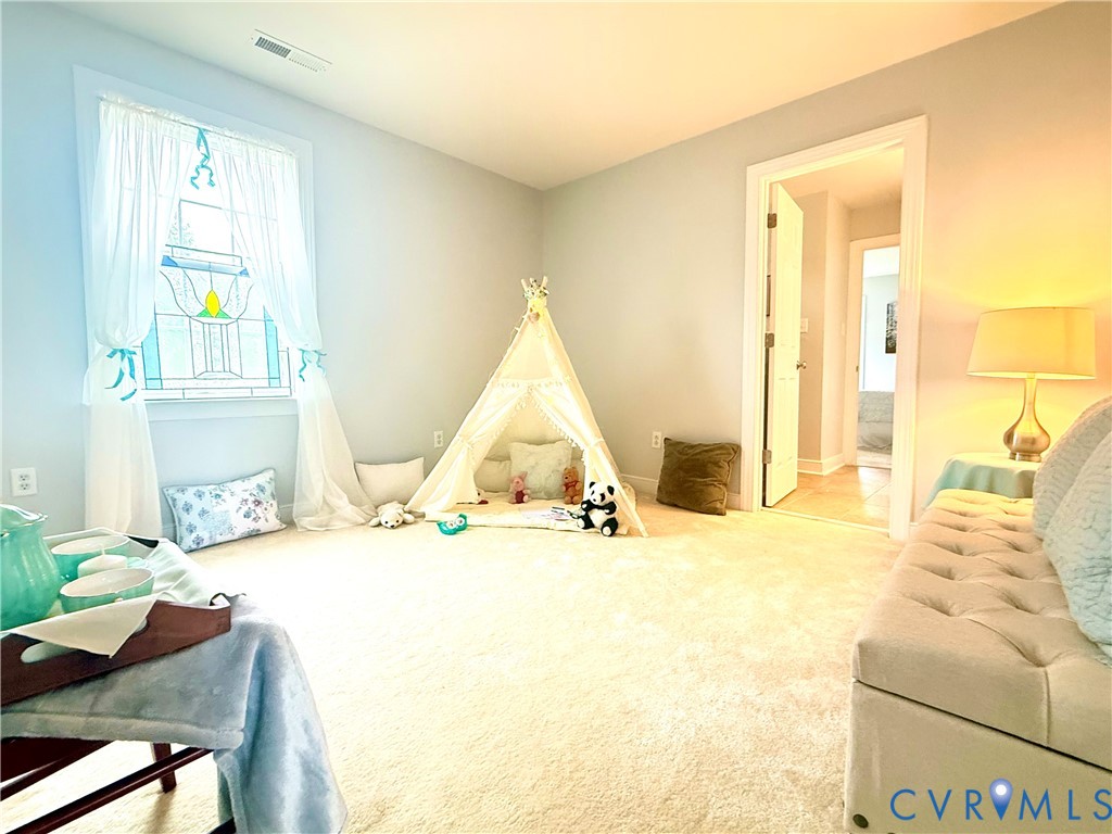 Spacious room featuring light-toned carpeting and a window with a decorative stained-glass accent