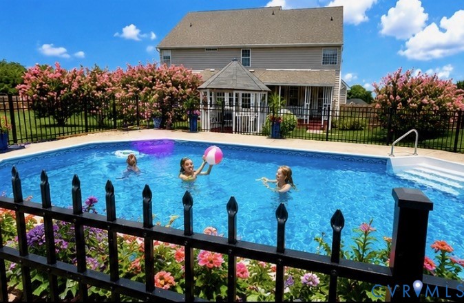 Backyard features a large in-ground swimming pool with integrated steps, surrounded by a black wrought iron fence Backyard features a large in-ground swimming pool with integrated steps, surrounded by a black wrought iron fence