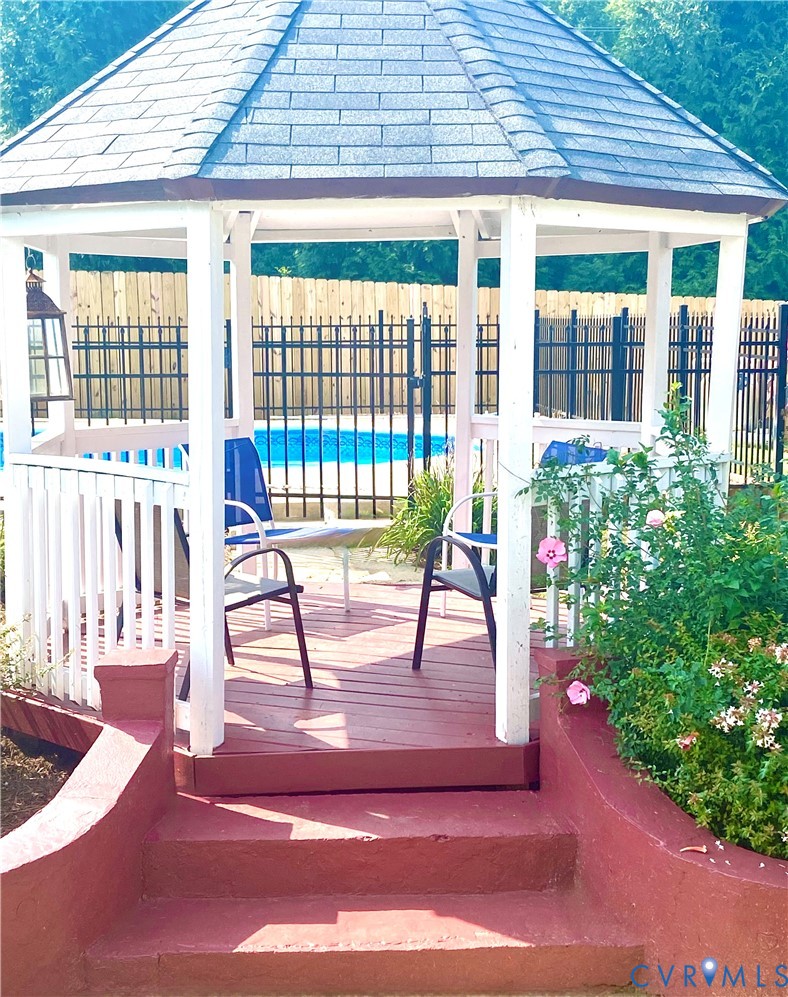 Spacious gazebo with a shingled roof, white balusters, and a wooden deck