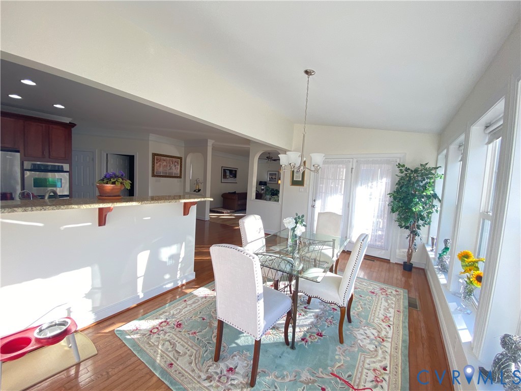 Bright dining area featuring multiple windows, a glass-top table, and a chandelier