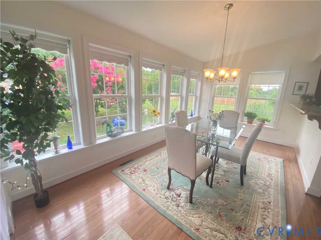 Bright dining area featuring wood-finish flooring and a vaulted ceiling