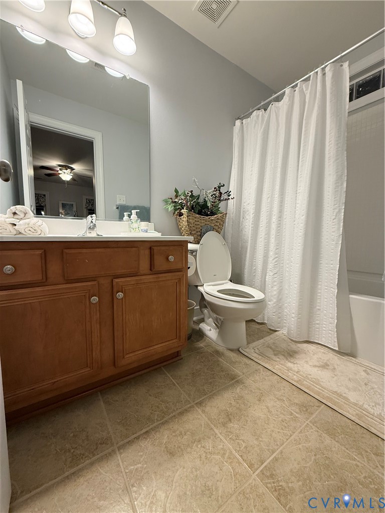 Bathroom featuring a wood-finish vanity with a double-basin sink, large wall mirror, and a full bathtub with an overhead shower