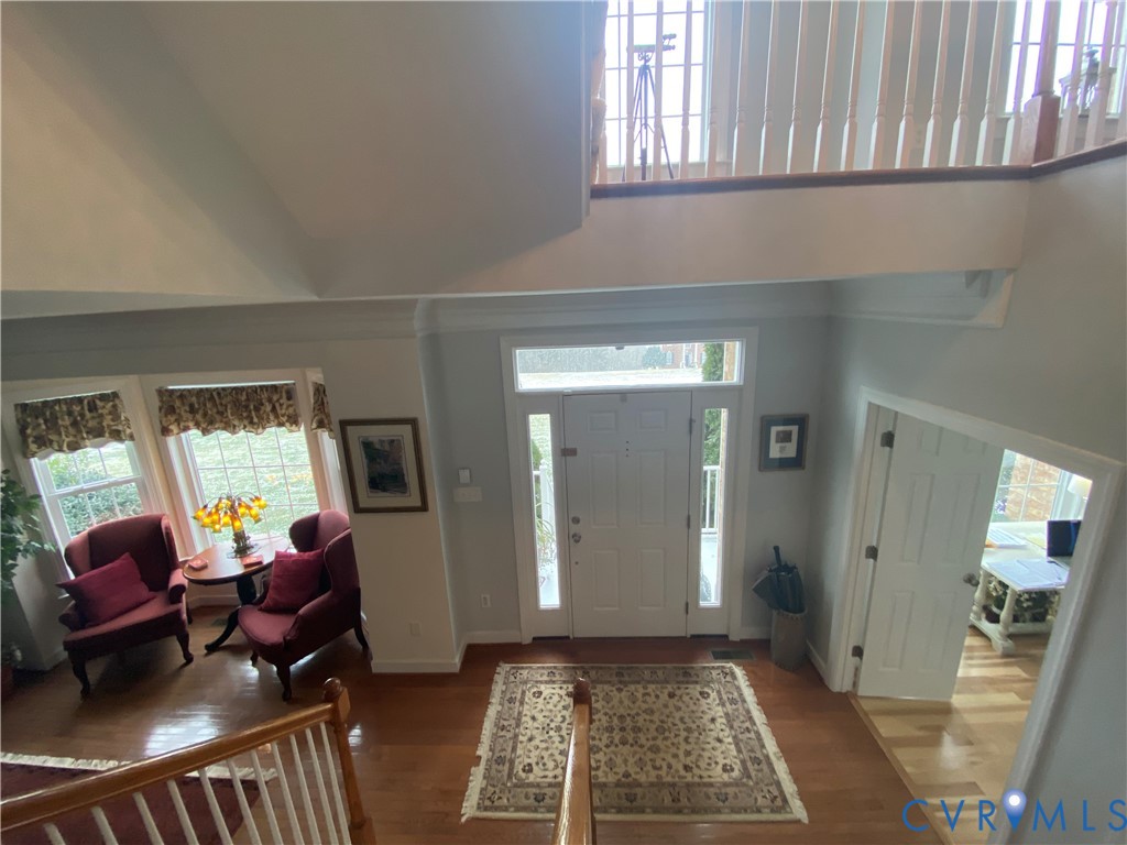 Two-story foyer featuring wood-finish flooring, a prominent white entry door with sidelights, and a second-story landing with wood railings
