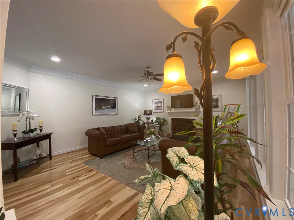 Living area featuring light wood-finish flooring, recessed lighting, crown molding, and a built-in fireplace with a mantel