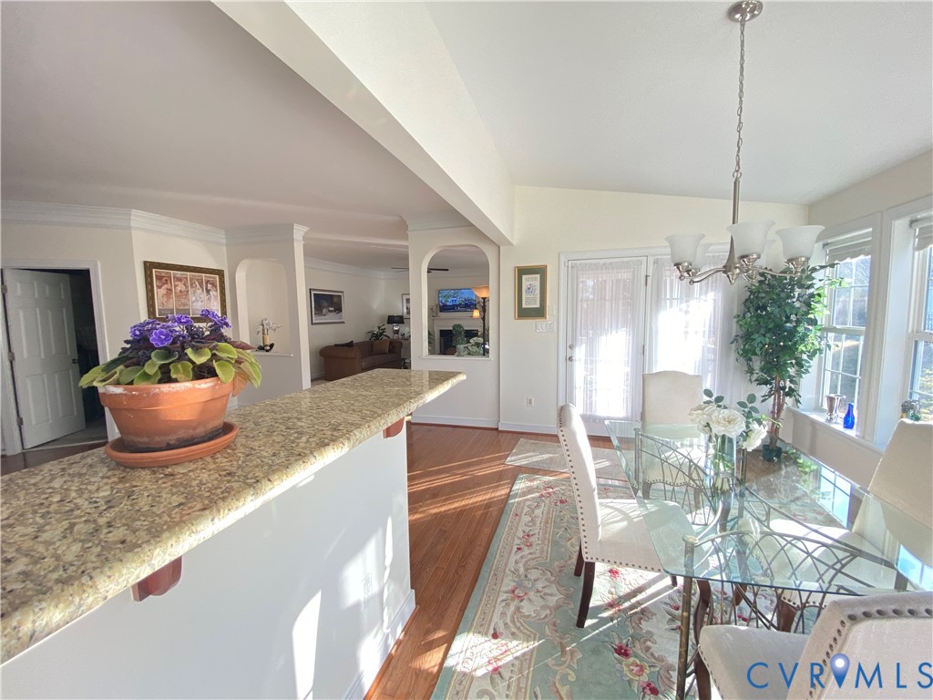 Dining area featuring a glass-top table, multiple windows, and a chandelier with frosted shades