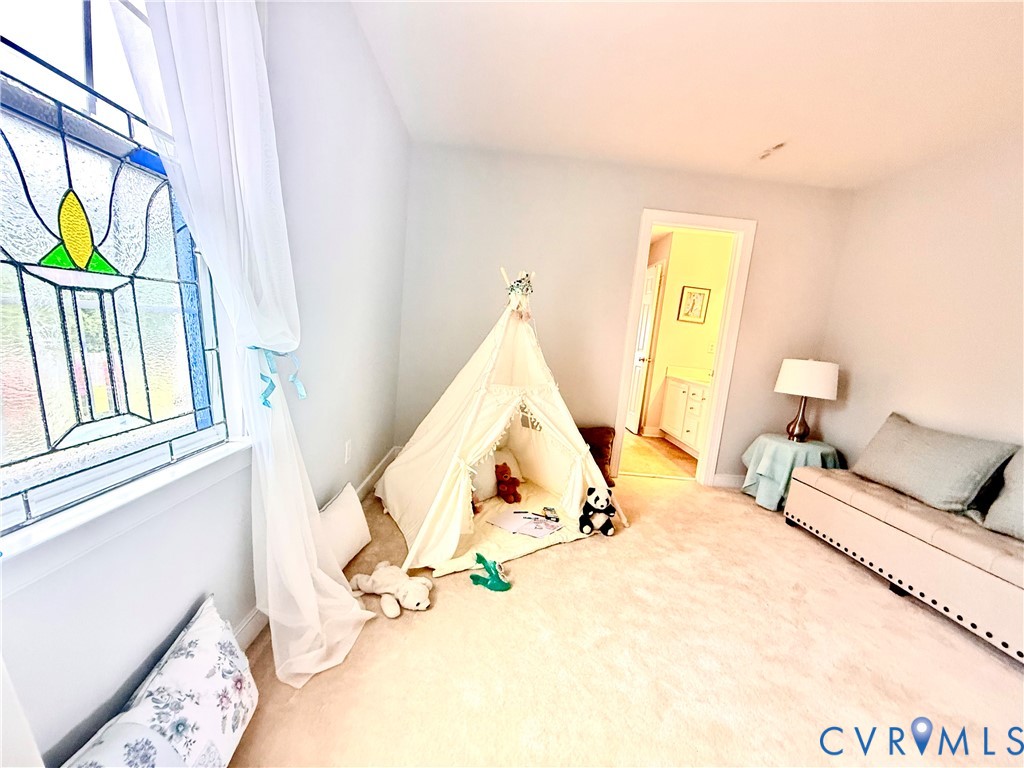 Room featuring light-colored carpet flooring, a window with stained glass detailing, and light gray wall paint