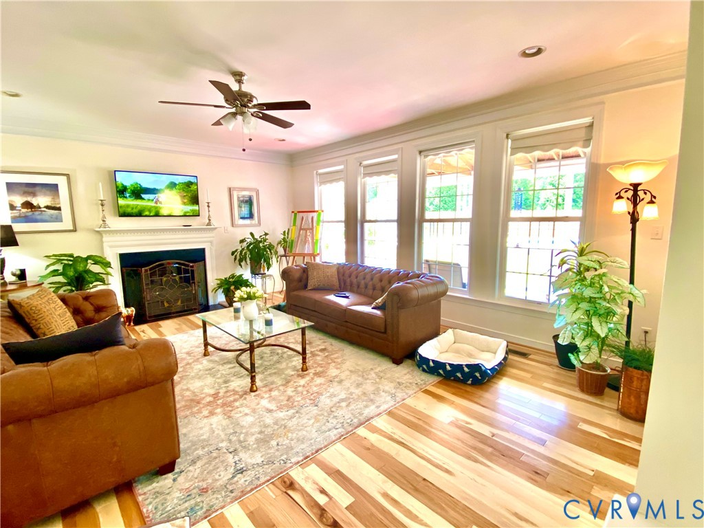 Living area featuring wood-finish flooring, a white mantelpiece, and a ceiling fan