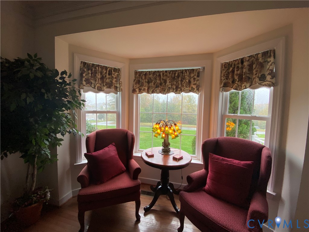 Bay window featuring three large windows, white trim, and patterned valances