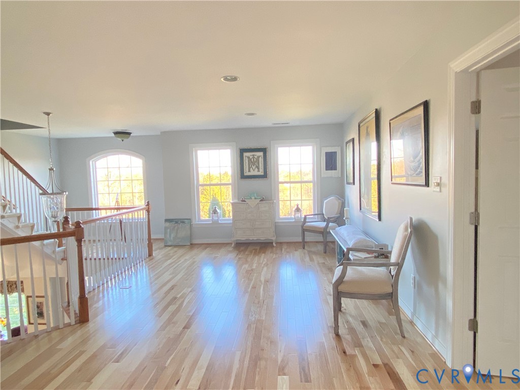 Bright upper-level landing featuring wood-finish flooring, a white spindle staircase with wood handrails, and a transom window