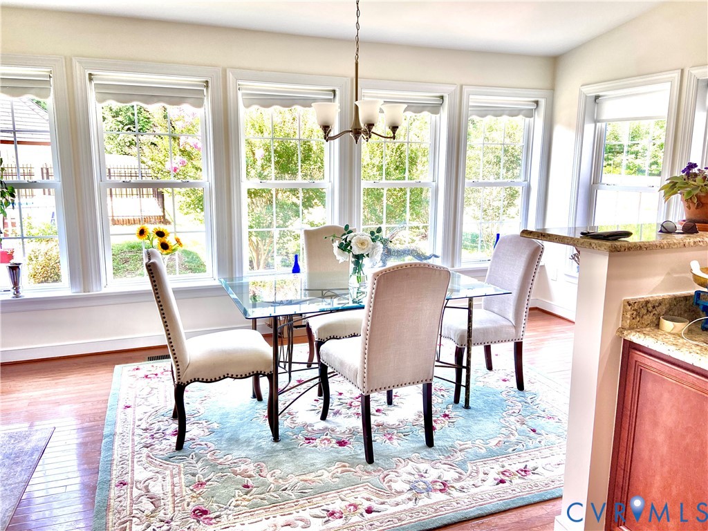 Dining area featuring a series of large windows with white trim, wood-finish flooring, and a built-in countertop with granite-style finish