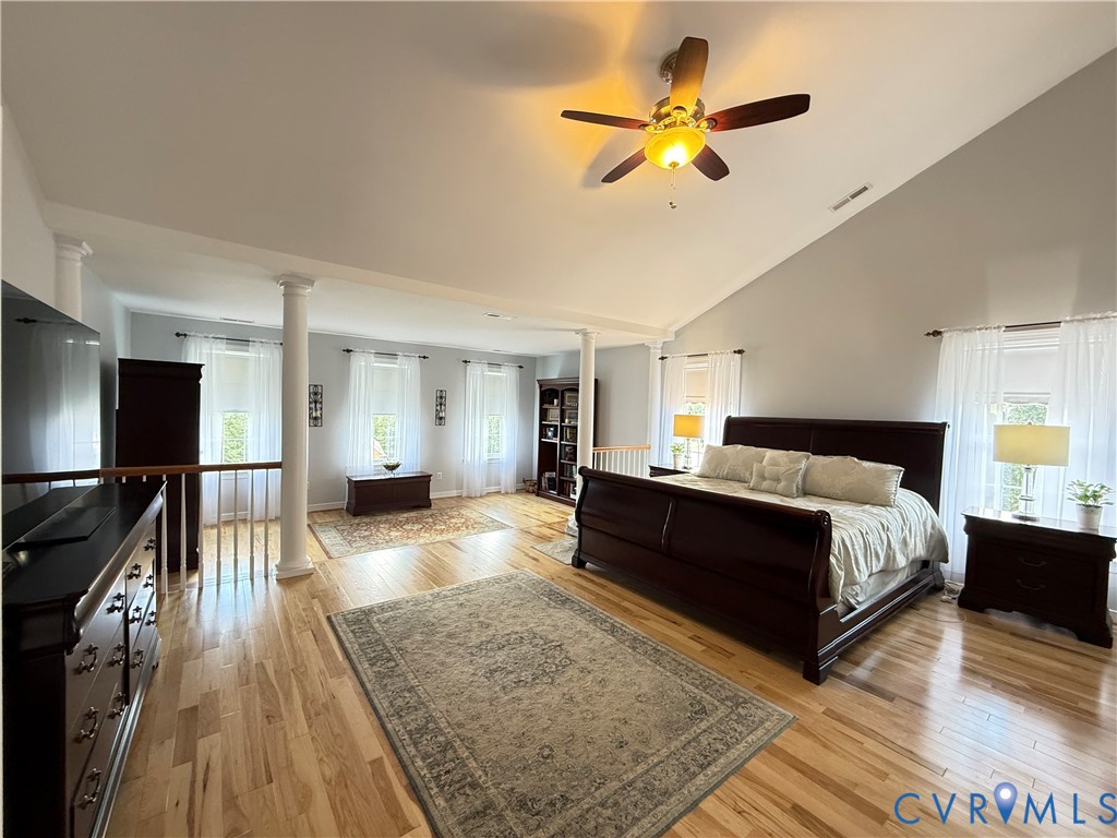 Spacious room featuring vaulted ceilings, light wood-finish flooring, and multiple windows