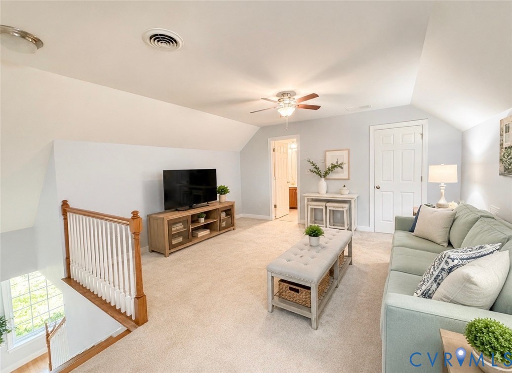 Carpeted loft area featuring a ceiling fan, sloped ceilings, and interior doors