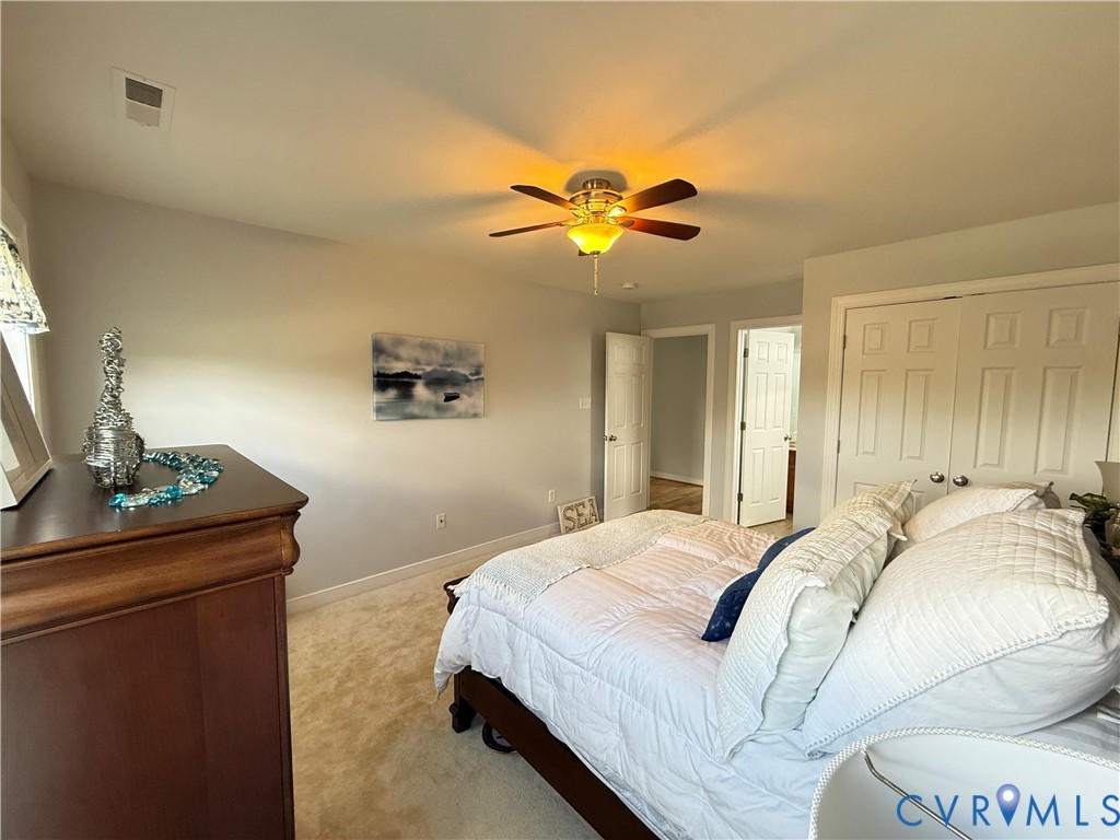 Carpeted room with a ceiling fan light fixture, two panel doors, and neutral wall paint
