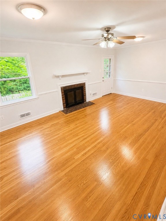 Spacious room featuring wood-finish flooring, a brick-surround fireplace with a white mantel, ceiling fan with integrated lighting, recessed lighting, and a glass-paneled door
