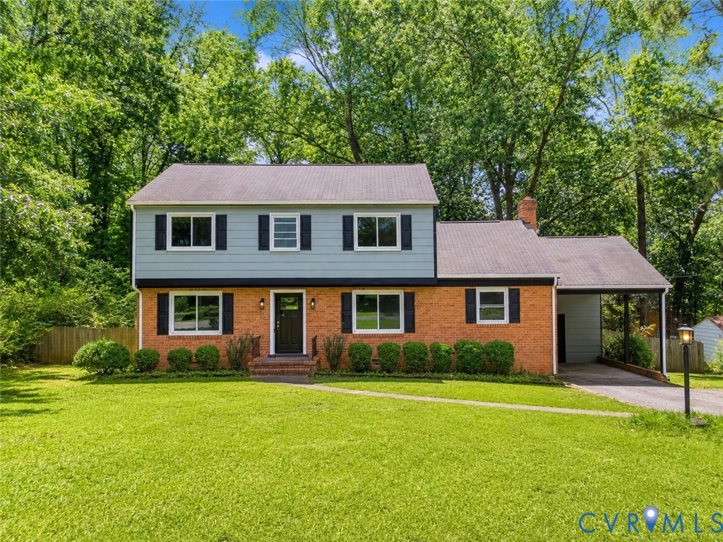 Brick and siding exterior featuring a covered carport, front entry porch, and mature landscaping