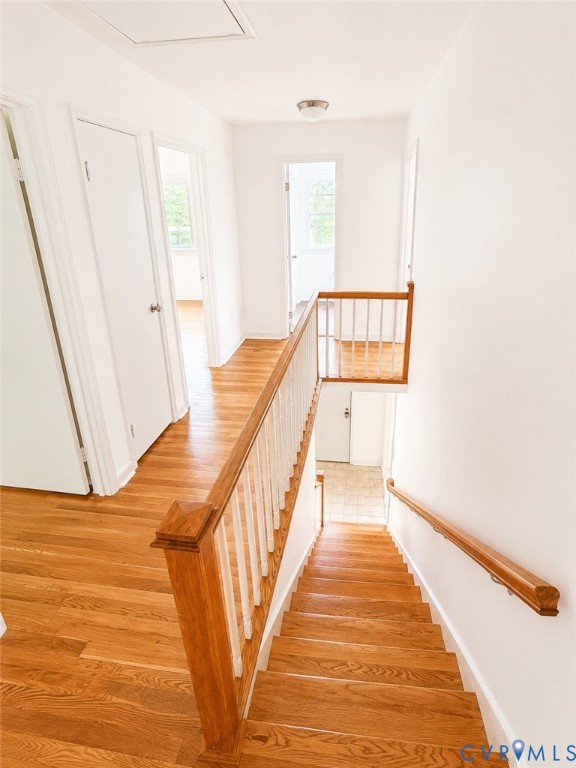 Hardwood flooring throughout the upper level and staircase, featuring a wood baluster railing, white walls, and flush-mount ceiling lighting
