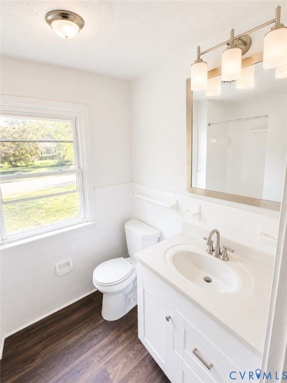 Bathroom featuring a white vanity with an integrated sink, brushed nickel faucet, and wood-finish flooring
