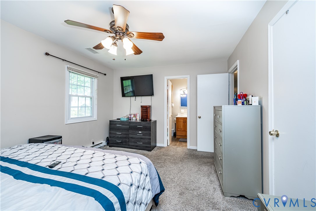 Carpeted bedroom featuring a double-hung window, ceiling fan with integrated lighting, and neutral wall tones