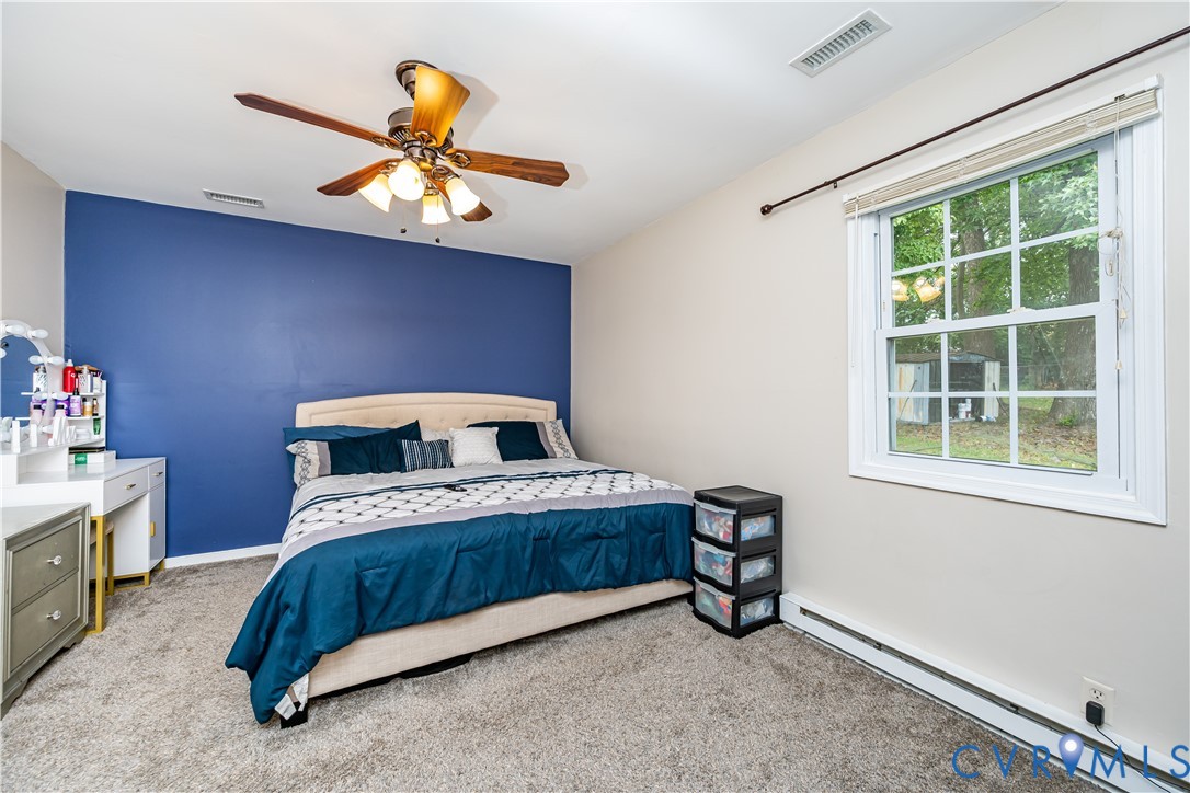 Bedroom featuring a vibrant accent wall, neutral carpeting, and a window with white framing