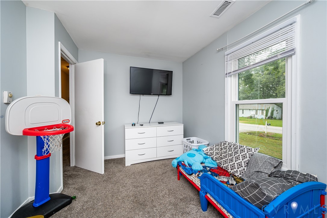 Carpeted room featuring light gray walls, a single window with blinds, and a white interior door