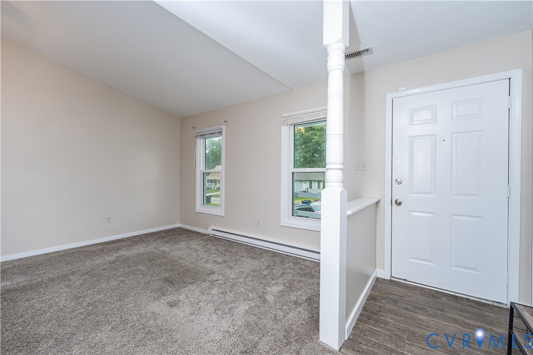 Entryway featuring wood-finish flooring, a white paneled door, and a decorative half-wall with an architectural column