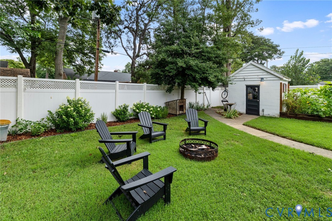 Expansive backyard featuring a manicured lawn, white vinyl privacy fence with lattice top, and mature trees