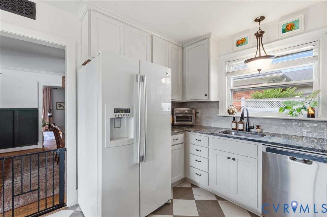 Kitchen featuring white cabinetry, grey and white checkerboard flooring, a stainless steel dishwasher, a black faucet, and a large window