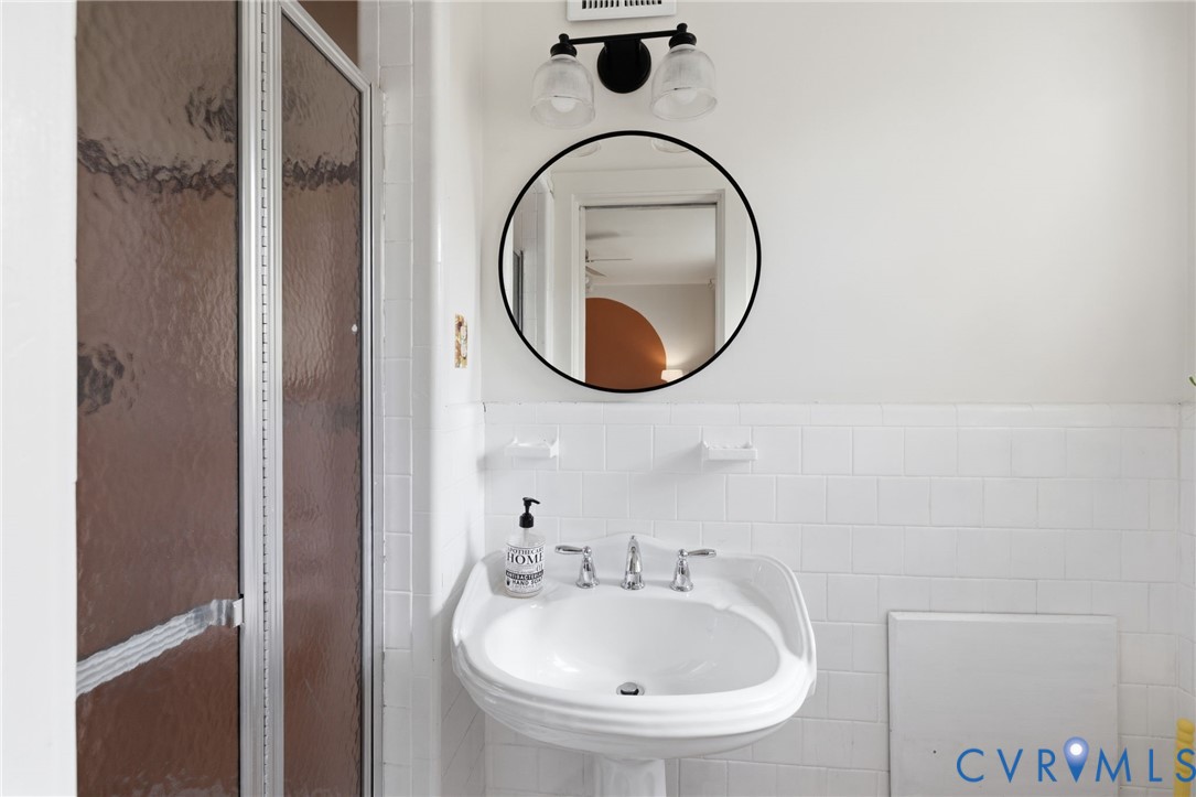 White tile wainscoting and a pedestal sink with a chrome faucet