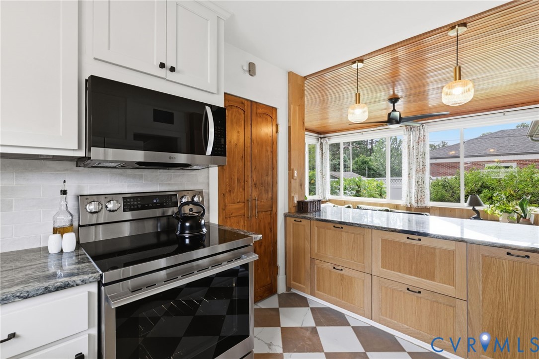 Kitchen featuring stainless steel appliances, white subway tile backsplash, and light wood cabinetry