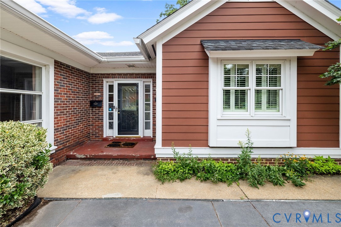 Exterior featuring a brick facade, horizontal siding, and white trim