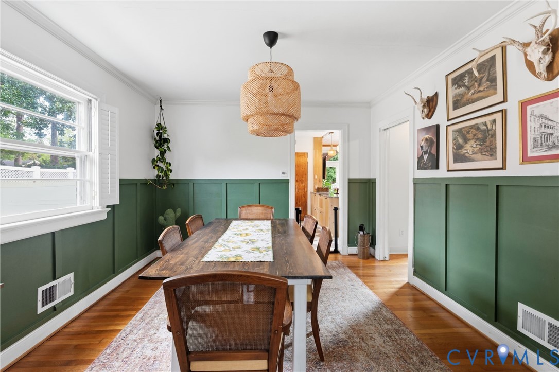 Dining area featuring wood-finish flooring, a contemporary woven pendant light fixture, and green board-and-batten wall detailing