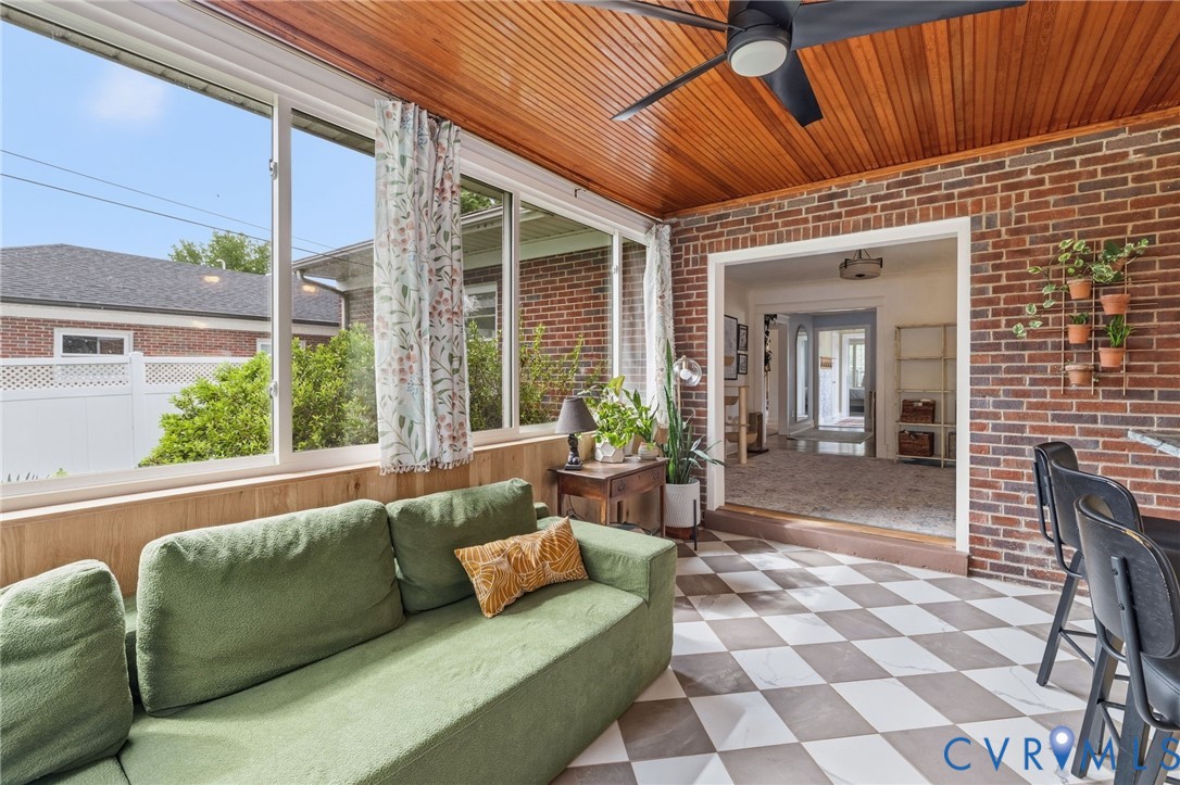 Sunroom featuring a wood-paneled ceiling with a ceiling fan, brick accent wall, checkerboard tile flooring, and extensive window panels