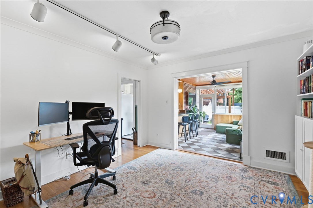 Hardwood flooring throughout, featuring a cased opening to an enclosed porch with checkerboard flooring
