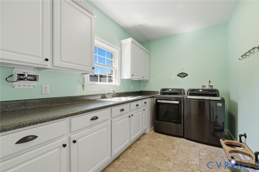 Laundry room featuring white cabinetry, dark countertops, a window, and tile flooring