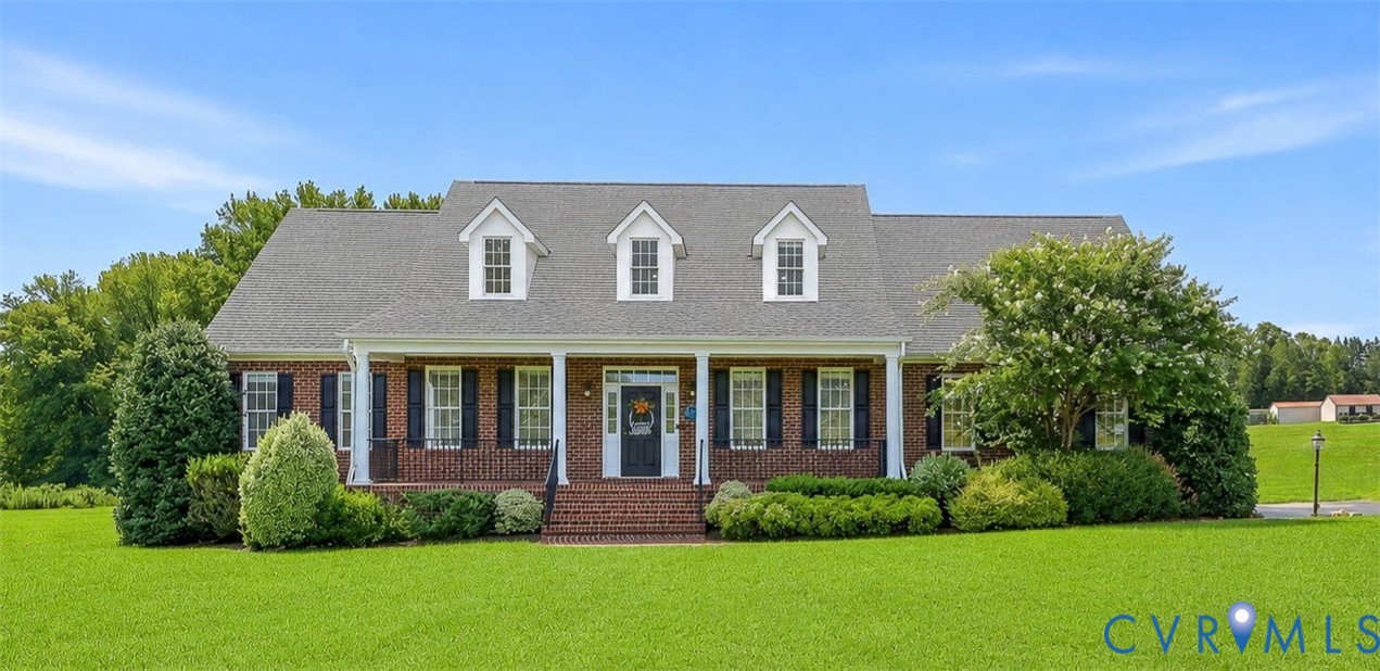 Brick facade residence featuring a covered front porch, white columns, and black shutters Brick facade residence featuring a covered front porch, white columns, and black shutters