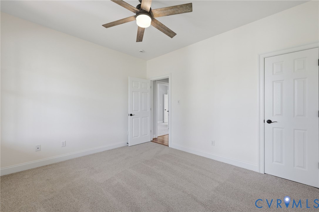 First Floor Guest bedroom Carpeted interior room featuring a ceiling fan with integrated lighting, white walls, and white trim