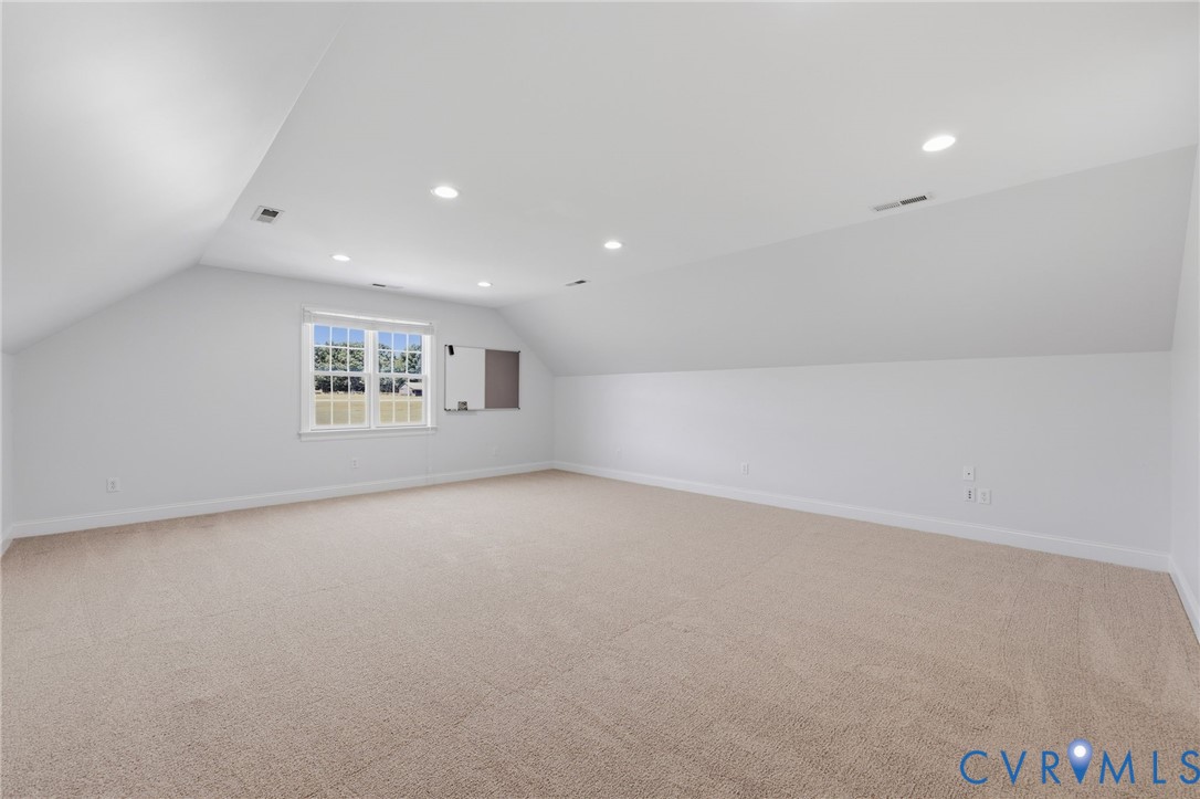 Spacious bonus room featuring neutral carpeting, recessed lighting, a double window, white walls, and sloped ceilings